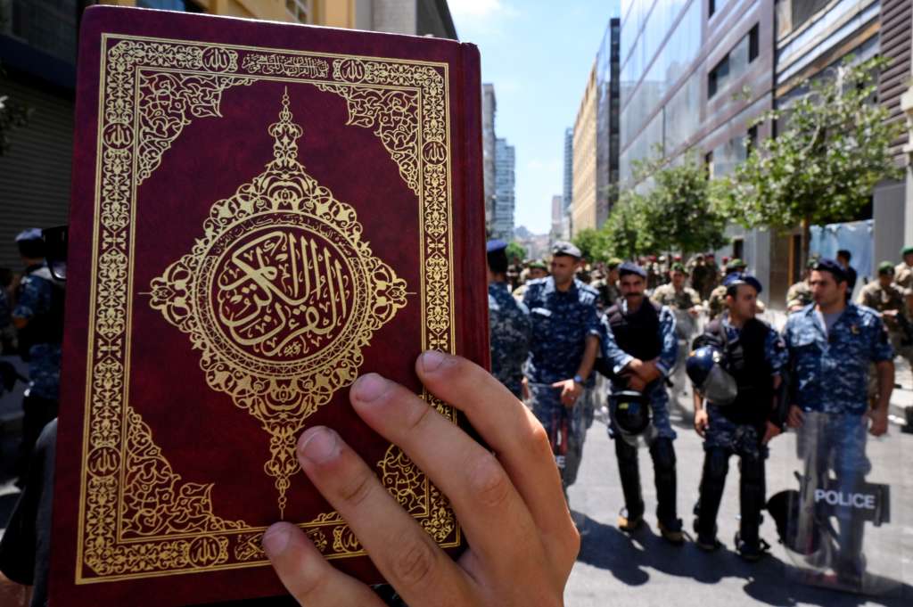 Beirut (Lebanon), 21/07/2023.- Lebanese police officers stand guard as a protester holds a copy of the Koran outside Sweden's embassy after Hezbollah leader called for protests outside mosques against the Koran desecration, in Beirut, Lebanon, 21 July 2023. Hezbollah leader Hassan Nasrallah called for protests outside mosques following Friday prayers to condemn what he called the desecration of the Koran in Sweden by anti-Islam protesters. (Protestas, Líbano, Suecia) EFE/EPA/WAEL HAMZEH