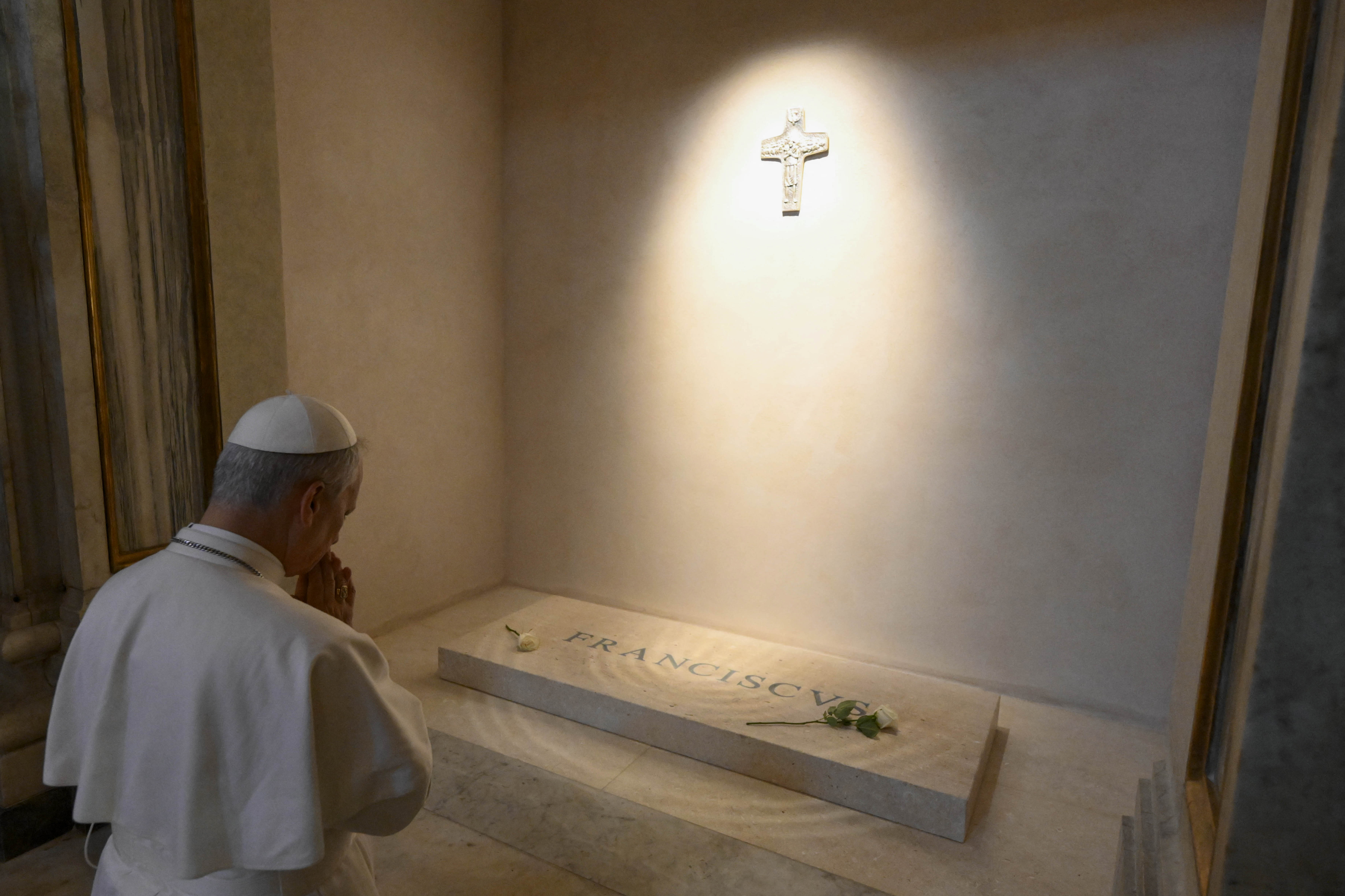 El papa León XIV reza frente a la tumba del difunto papa Francisco.