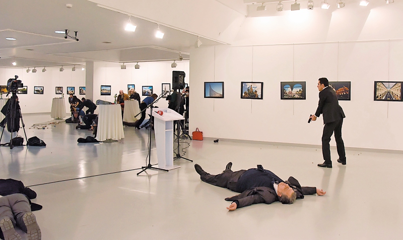 Mevlüt Mert Altintas (de pie, con su pistola) grita ante el público en una galería de Ankara tras asesinar al embajador ruso Andréi Karlov (en el suelo). / AFP