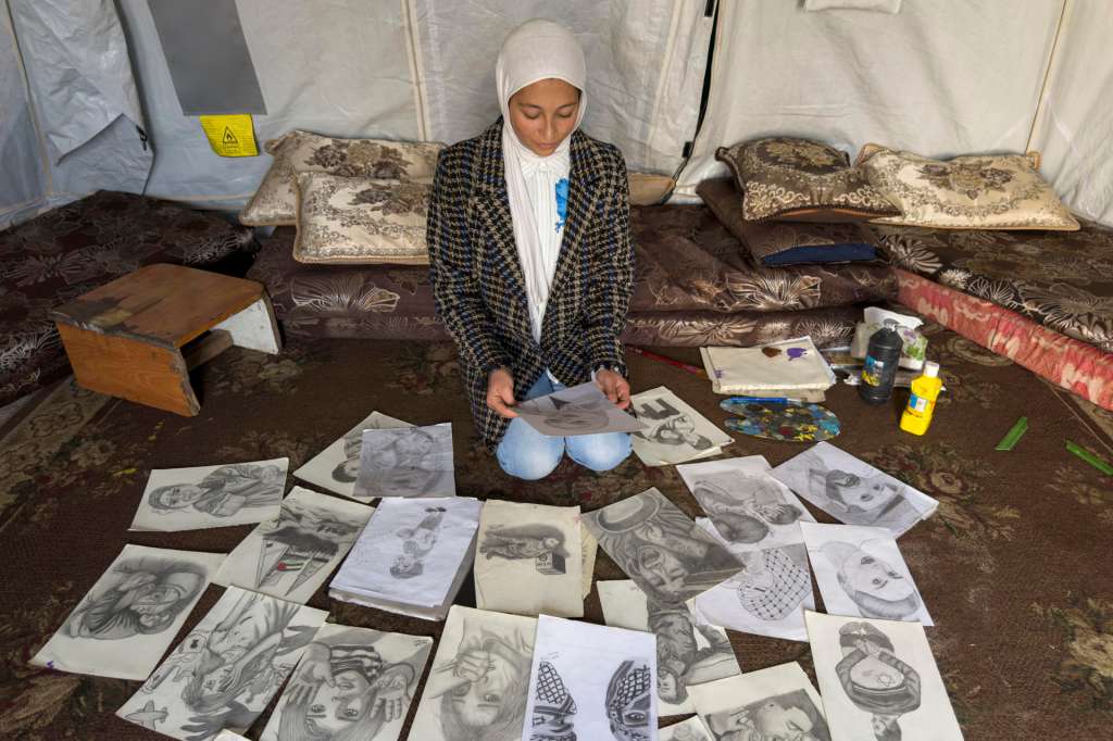 Gaza, 01/01/2026.- La hambruna, los misiles, la muerte y las tiendas en las que malviven cientos de miles de personas cobran vida con las pinceladas que la joven gazatí Sarah Fadl Saadeh lleva dos años dando a sus lienzos mientras sufre el desplazamiento de un lado a otro de la Franja palestina, lo que le ha permitido narrar el dolor de su pueblo en primera persona. EFE/Ahmad Awad