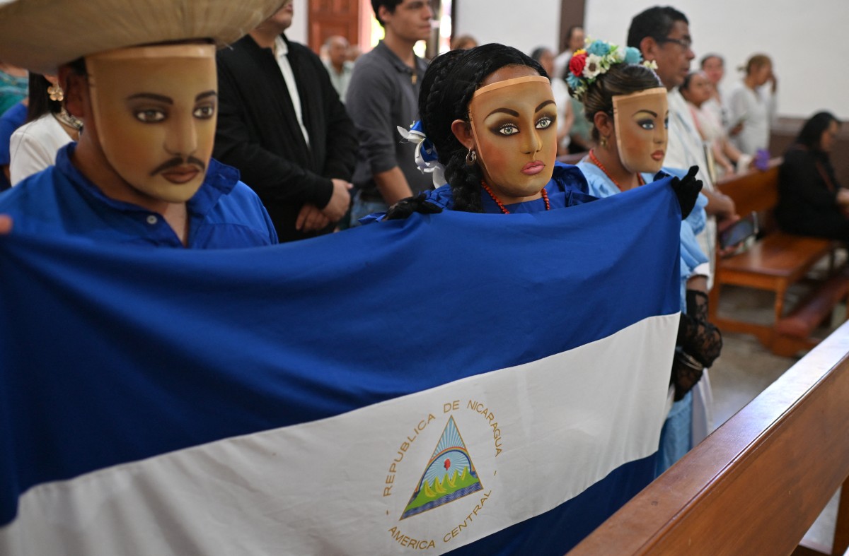 Masked Nicaraguans living in exile, holding a Nicaraguan flag, attend Mass at the Church of San Francisco in San Jose, Costa Rica, on April 19, 2026.