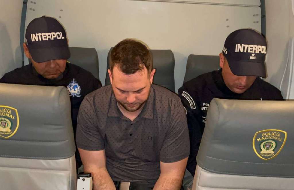 John Poulos viaja en un avión privado custodiado por las autoridades colombianas.
