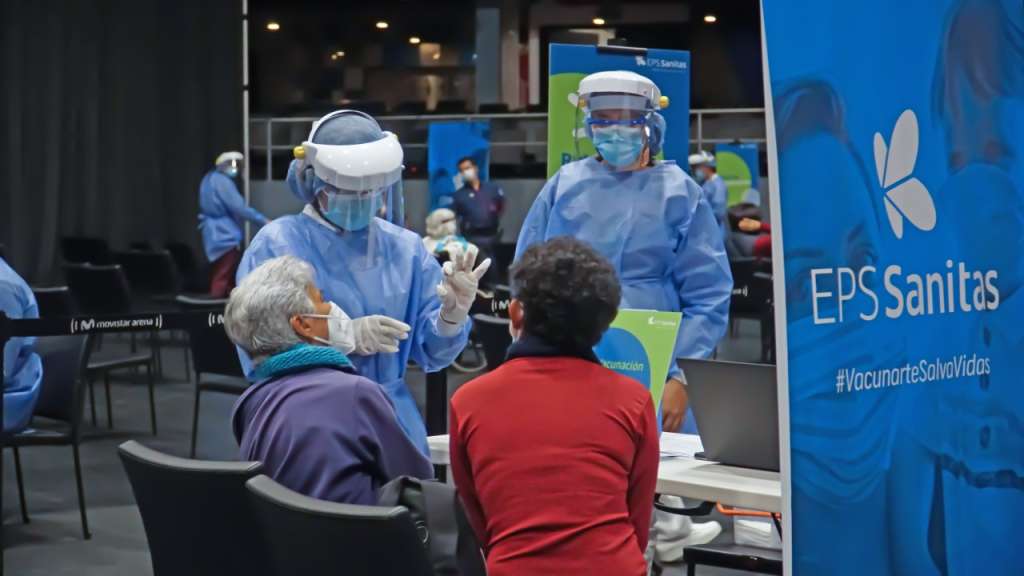 Una mujer muestra a dos mujeres la vacuna.