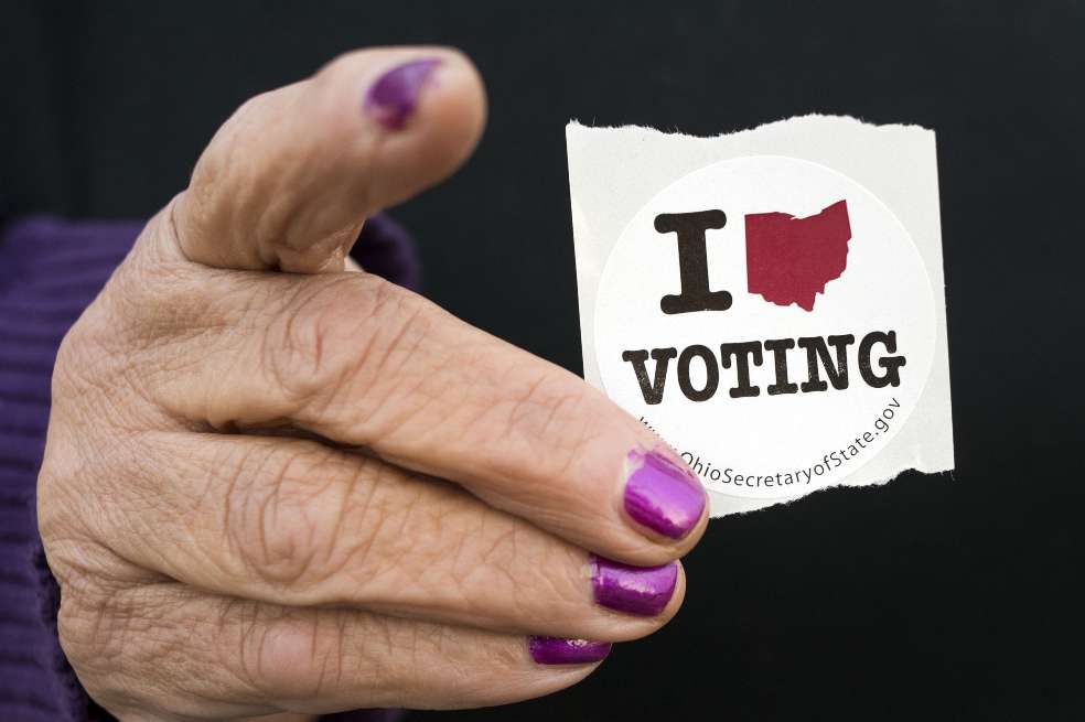 Una mano sujeta un sticker de voto estadounidense.