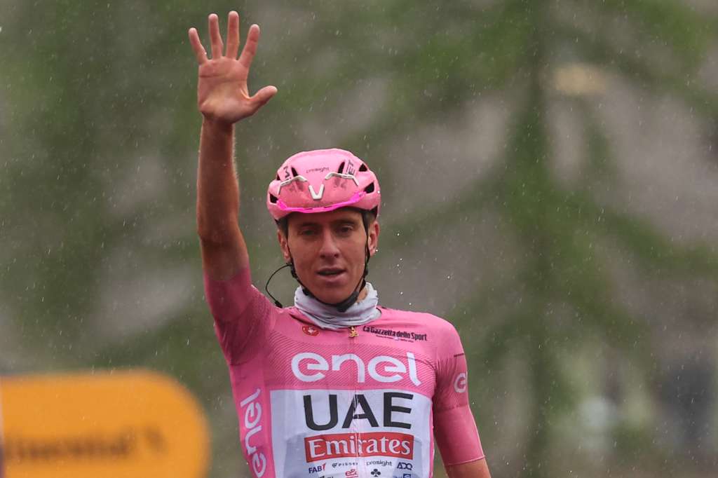 Tadej Pogačar levanta la mano en la meta, señalando sus cinco victorias en el Giro de Italia 2024.