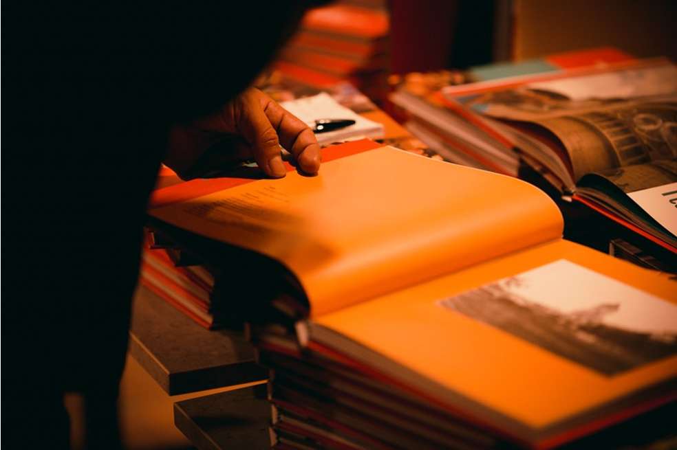 Foto de una persona viendo un libro. El libro está abierto y la mano izquierda de la persona está apoyada en él.