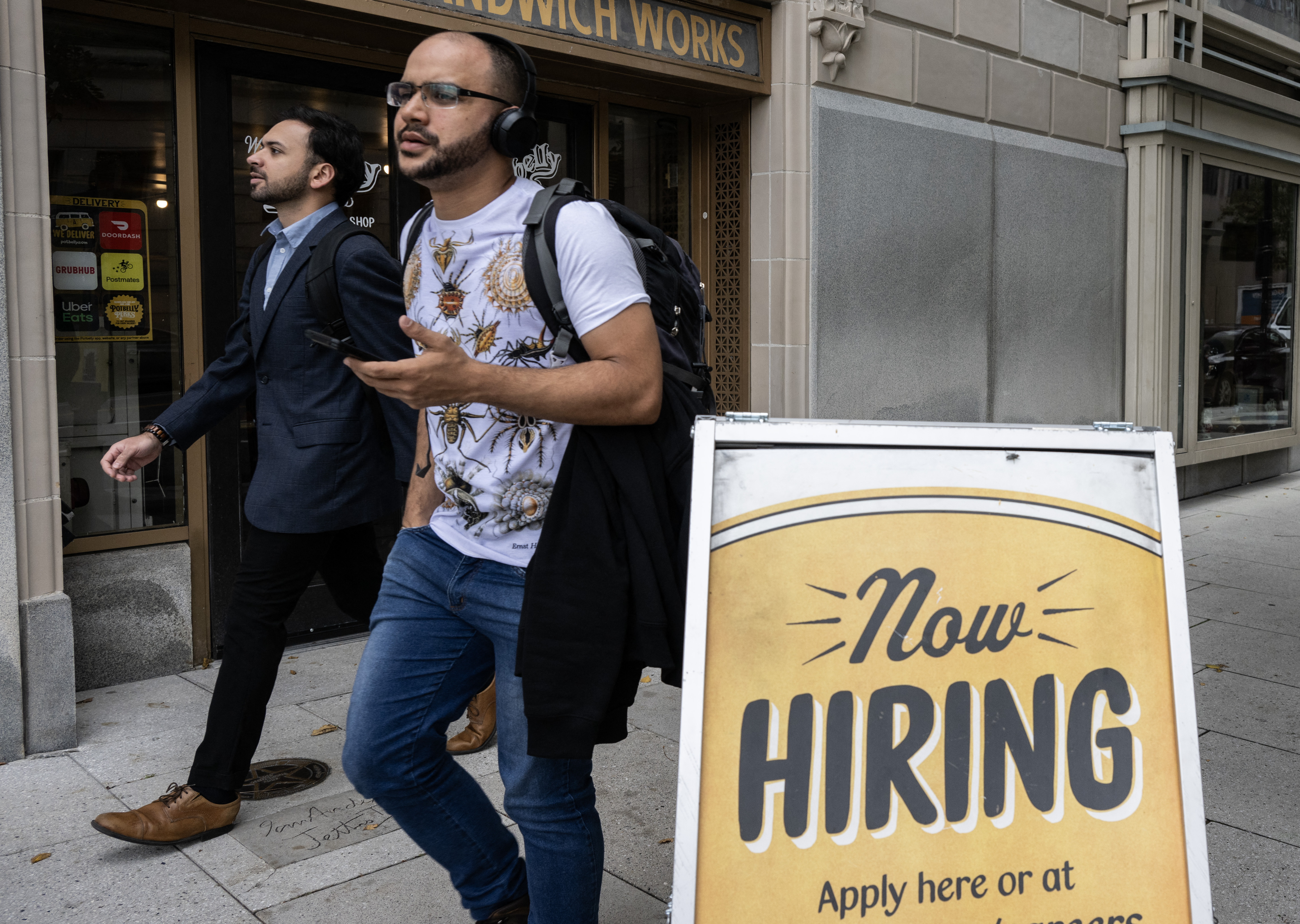 (FILES) People walk past a restaurant, with a hiring sign outside, in Washington, DC on October 5, 2023.