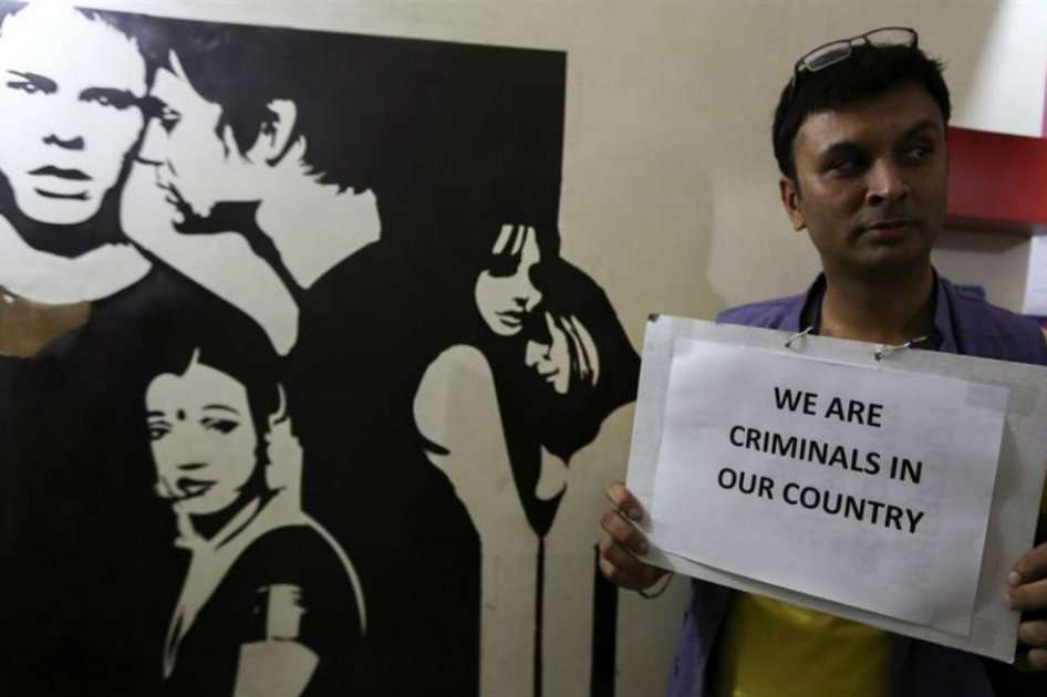 Un activista sostiene una pancarta en la que se puede leer "En nuestro país somos criminales" mientras se suceden manifestaciones contra del veredicto del Tribunal Supremo en el que restableció la ilegalidad de las relaciones sexuales entre homosexuales, cuatro años después de que fueran despenalizadas