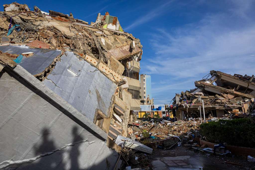 AME6165. LA GUAIRA (VENEZUELA), 30/06/2026.- Rescatistas de Vietnam caminan este martes sobre escombros de edificaciones destruidas en Catia La Mar, La Guaira (Venezuela). La cifra de fallecidos por el doble terremoto ocurrido el pasado miércoles en la zona norte de Venezuela ascendió a 1.943 y la de heridos a 10.571, informó el presidente del Parlamento, Jorge Rodríguez. EFE/ Miguel Gutiérrez
