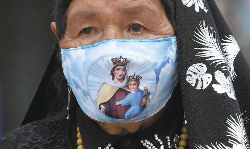 A Catholic devotee wearing a face mask as a precautionary measure against the spread of the novel coronavirus disease, COVID-19, attends a Holy Week celebration on Good Friday, at Bolivar square in Bogota on April 2, 2021.
  / AFP / Raul ARBOLEDA
