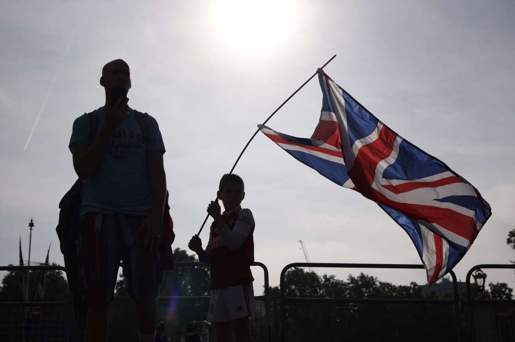 -FOTODELDIA- Londres (Reino Unido), 11/09/2022.- Un niño ondea la bandera británica en frente del Palacio de Buckingham como forma de homenaje tras la muerte de Isabel II en Londres, Reino Unido este domingo. El cortejo fúnebre con los restos mortales de la reina Isabel II salió este domingo del castillo escocés de Balmoral, donde murió el jueves a los 96 años, para iniciar el recorrido hasta Edimburgo, capital de Escocia. El ataúd de roble de la soberana está cubierto con el estandarte real de Escocia y sobre éste se ha depositado una corona de flores. EFE/ Yoan Valat