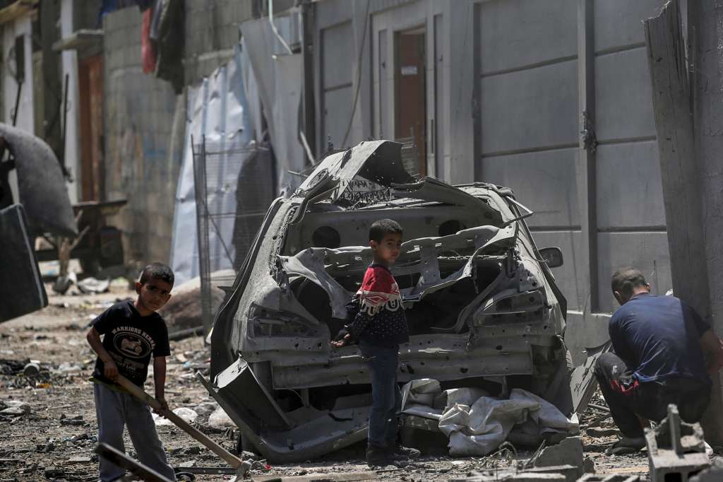Maghazi Camp (-), 15/04/2024.- A Palestinian man with two children among destroyed buildings near a damaged car in Al Maghazi refugee camp, central Gaza Strip, 15 April 2024, following Israeli air strikes. More than 33,700 Palestinians and over 1,450 Israelis have been killed, according to the Palestinian Health Ministry and the Israel Defense Forces (IDF), since Hamas militants launched an attack against Israel from the Gaza Strip on 07 October 2023, and the Israeli operations in Gaza and the West Bank which followed it. EFE/EPA/MOHAMMED SABER