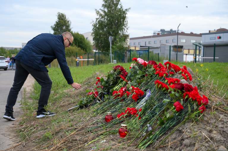 Un hombre lleva flores a un monumento conmemorativo informal junto al antiguo 'Centro Wagner PMC' en San Petersburgo, Rusia, 24 de agosto de 2023, un día después de que se reportara que Yevgueni Prigozhin, líder del grupo paramilitar, iba a bordo de un avión que se siniestró, sin dejar sobrevivientes, en Rusia.