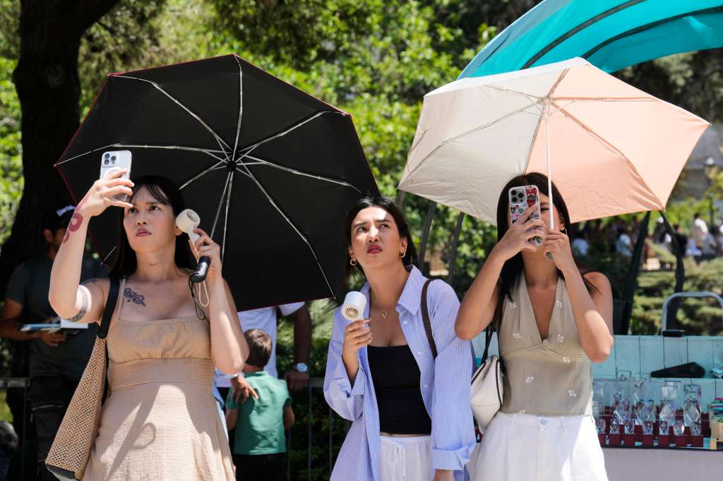 BARCELONA, 28/06/2025.- Unas turistas utilizan sombrillas para protegerse del sol frente a la Sagrada Familia en Barcelona este sábado. Catorce comunidades están este sábado en alerta por temperaturas excepcionalmente altas en el día de inicio de la primera ola de calor del verano en España. EFE/ Alejandro García
