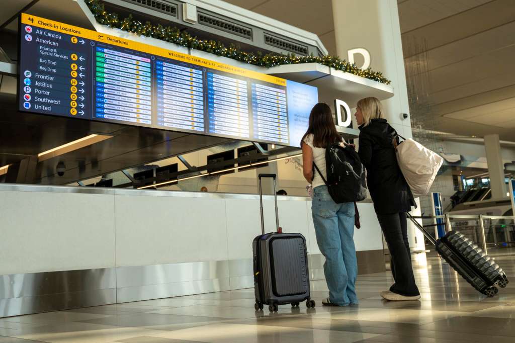 AMDEP8659. NUEVA YORK (ESTADOS UNIDOS), 07/11/2025.- Personas miran el estado de vuelos en las pantallas del aeropuerto de La Guardia este viernes, en Nueva York (EE.UU.). Debido a la escasez de controladores agudizada por el cierre del Gobierno Federal, EE.UU. recorta a partir del viernes en un 10 % la oferta de vuelos en 40 grandes aeropuertos, medida que puede eliminar hasta 4.000 correspondencias diarias en el mayor mercado mundial de la aviación comercial. EFE/Ángel Colmenares
