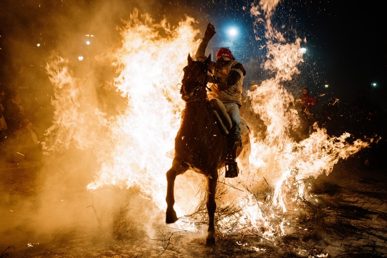 FOTOGALERÍA 5 DE 10.- SAN BARTOLOMÉ DE PINARES (ÁVILA), 16/01/2023.- Un jinete pasa con su caballo por encima de las llamas durante las tradicionales "luminarias" que se celebran hoy lunes en la localidad abulense de San Bartolomé de Pinares. EFE / Raúl Sanchidrián.