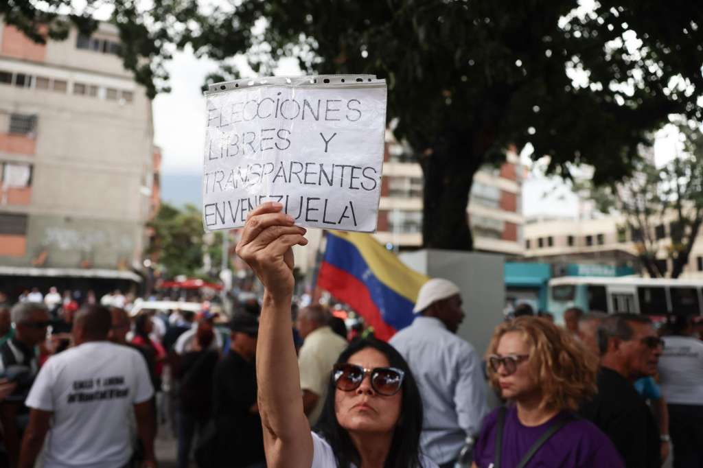 AME8400. CARACAS (VENEZUELA), 12/08/2026.- Una mujer sostiene un cartel durante una manifestación para pedir mejoras laborales este miércoles, mientras la primera ronda de negociación entre el Gobierno y la oposición de Venezuela, promovida por Estados Unidos, ocurre al interior del hotel Meliá Caracas, en Caracas (Venezuela). EFE/ Miguel Gutiérrez
