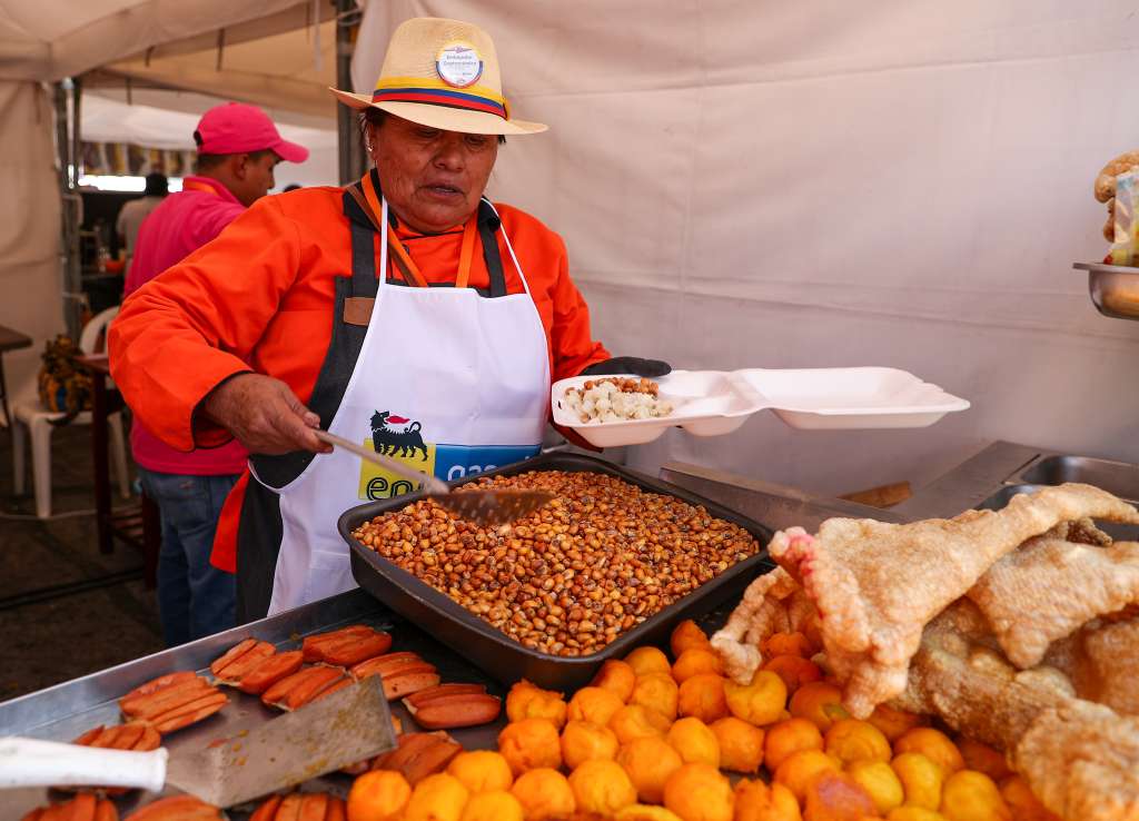 AME9227. QUITO (ECUADOR), 09/08/2024.- Una mujer sirve alimentos típicos, este jueves en Quito (Ecuador). La gastronomía tradicional de Ecuador se revindica esta semana en el Hueca Fest, uno de los festivales gastronómicos más importantes del país, que en su tercera edición espera recibir en Quito a más de 40.000 visitantes para saborear emblemáticos platos típicos como la fritada, el hornado, el ceviche ecuatoriano o el maito. EFE/ José Jácome