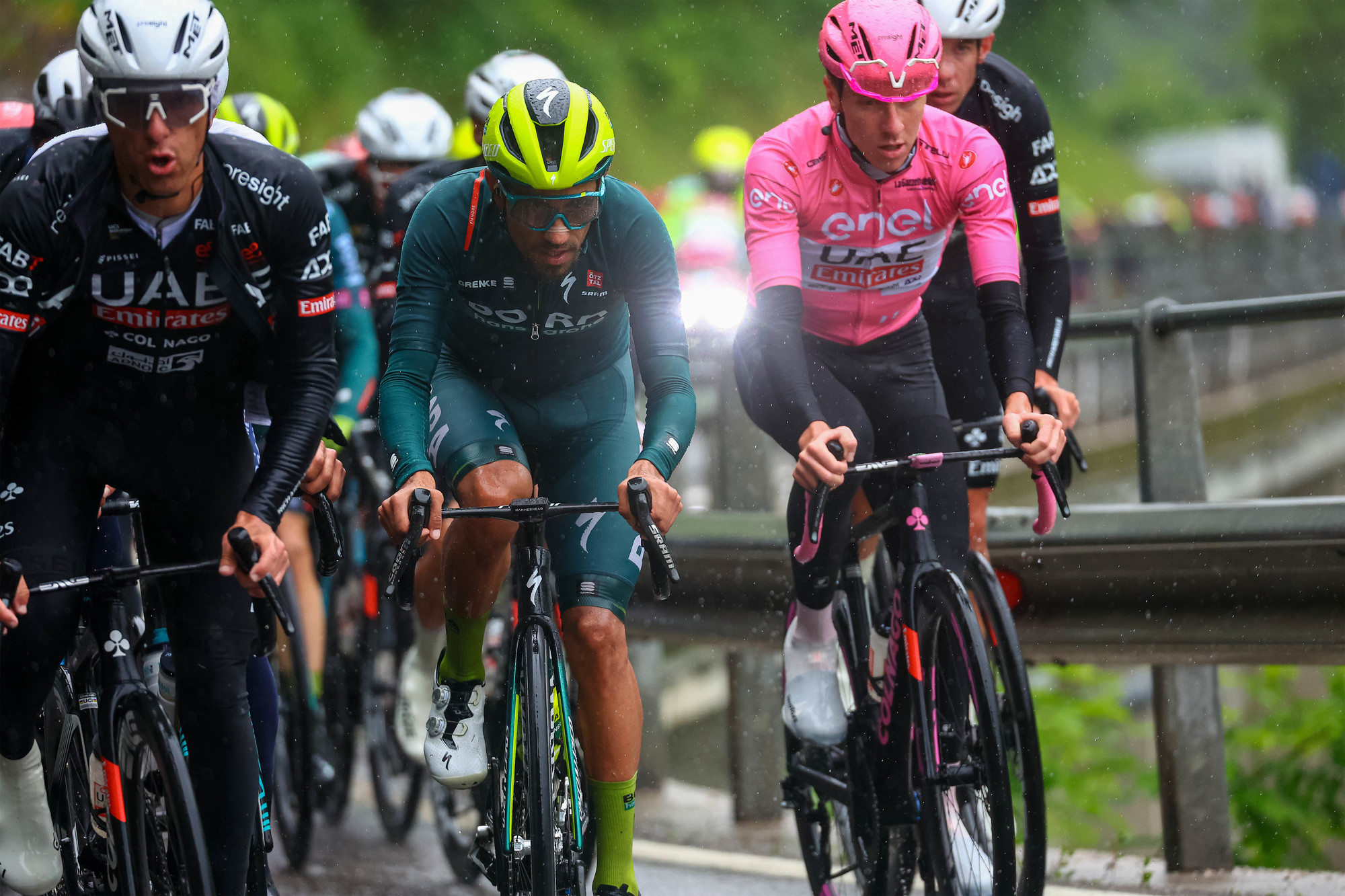 El colombiano Daniel Felipe Martínez (centro) al lado del hombre que luce la camiseta rosada de líder del Giro, Tadej Pogacar.