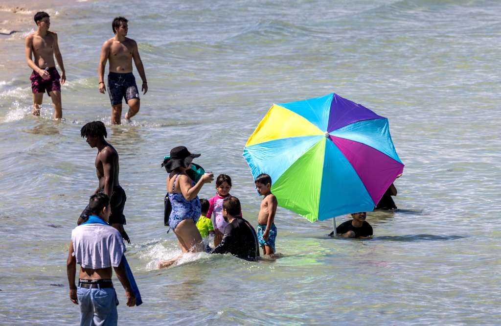 Miami Beach (Usa), 30/07/2023.- A beachgoer uses a beach umbrella to cover himself during the hottest summer in modern history, in Miami Beach, Florida, USA, 30 July 2023. According to NASA, the heat stored in the ocean causes its water to expand, which is responsible for one-third to one-half of global sea level rise. Most of the added energy is stored at the surface, at a depth of zero to 700 meters. The last 10 years were the ocean'Äôs warmest decade since at least the 1800s. The year 2022 was the ocean'Äôs warmest recorded year and saw the highest global sea level. EFE/EPA/CRISTOBAL HERRERA-ULASHKEVICH