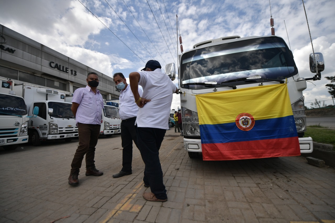 Fotografía de conductores de camiones reunidos en un parqueadero momentos antes de la movilización con una bandera de Colombia.